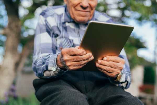 Elder man holds a tablet in his hands.